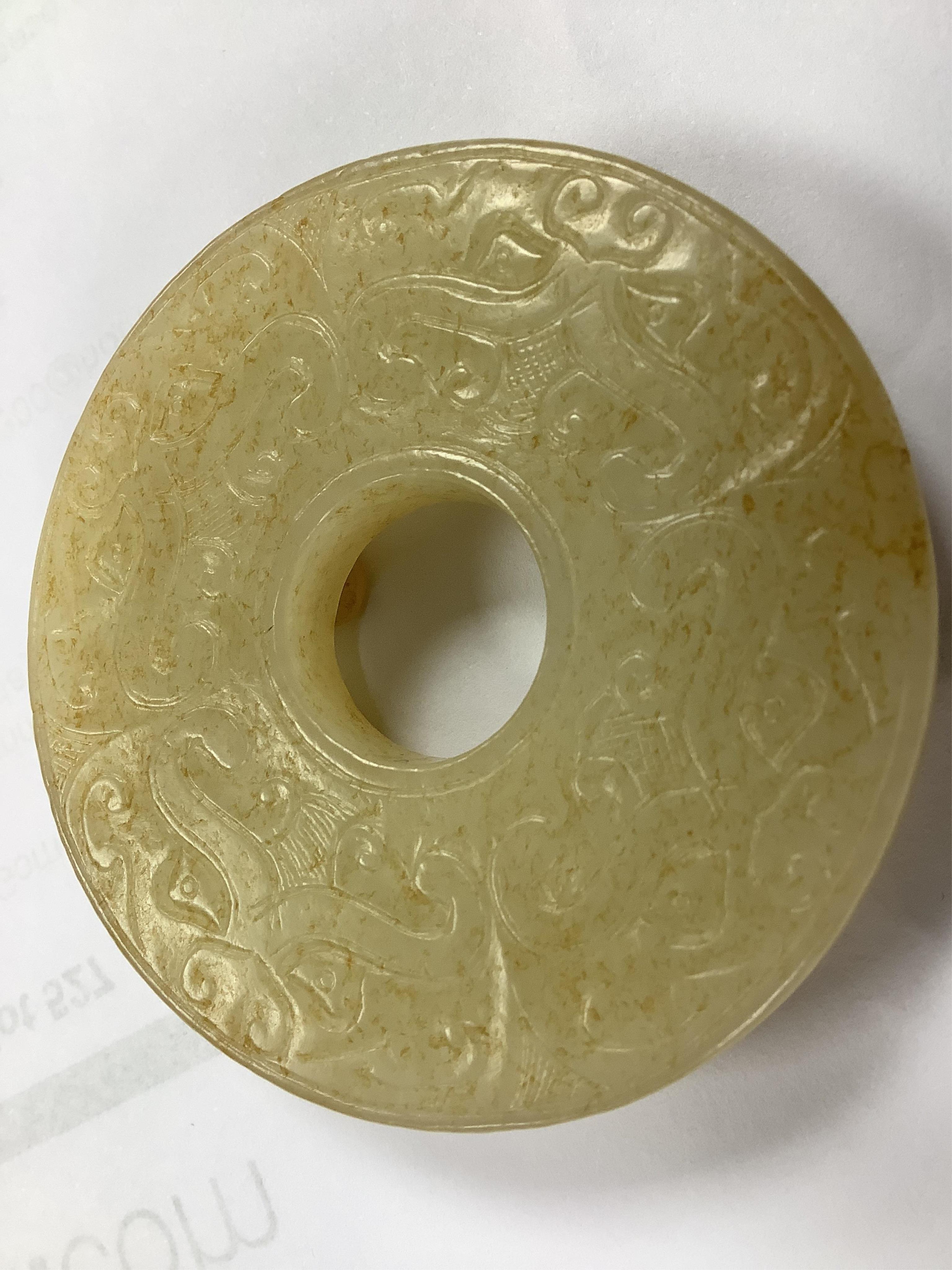 An 18th century Chinese mottled jade bi disc, decorated with two carved chilong, 5.8cm diameter